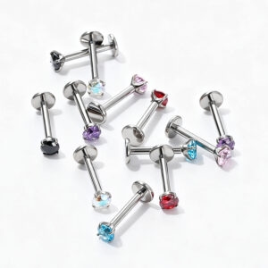 Mixed colors of titanium internally threaded CZ labret studs scattered on a white background